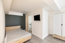 An en suite bedroom in 34 Park Street which has a double bed, a television mounted on the opposite wall to the bed and a large wardrobe